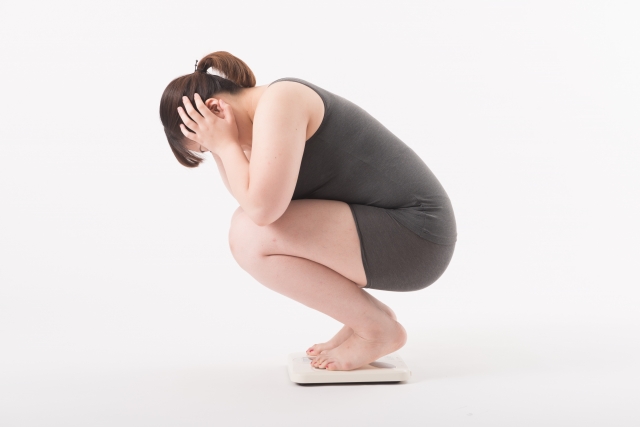 体重計に乗って落ち込む女性